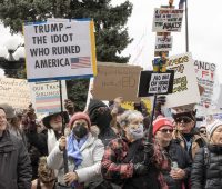 Protesters wave signs at anti-Trump rally, Denver, 4/5/25. Photo: Beth Schneider