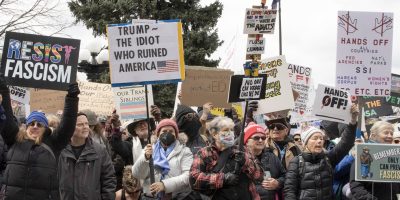 Protesters wave signs at anti-Trump rally, Denver, 4/5/25. Photo: Beth Schneider