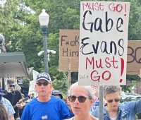 Protester in Greeley Saturday carrying a sign that says Gabe Evans Must Go!